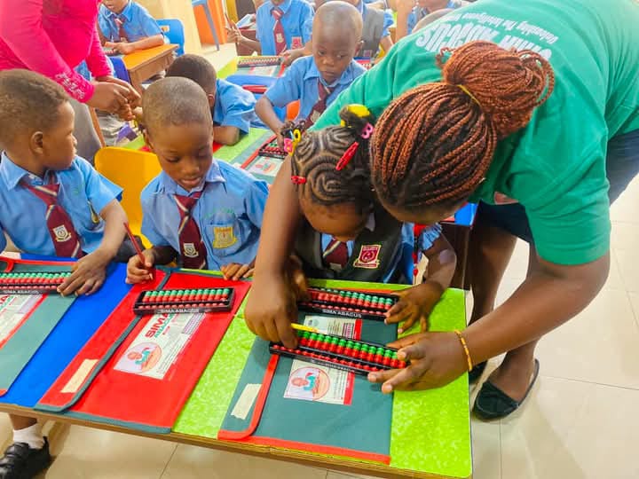 Nigerian school children learning abacus with teacher guidance in a classroom setting